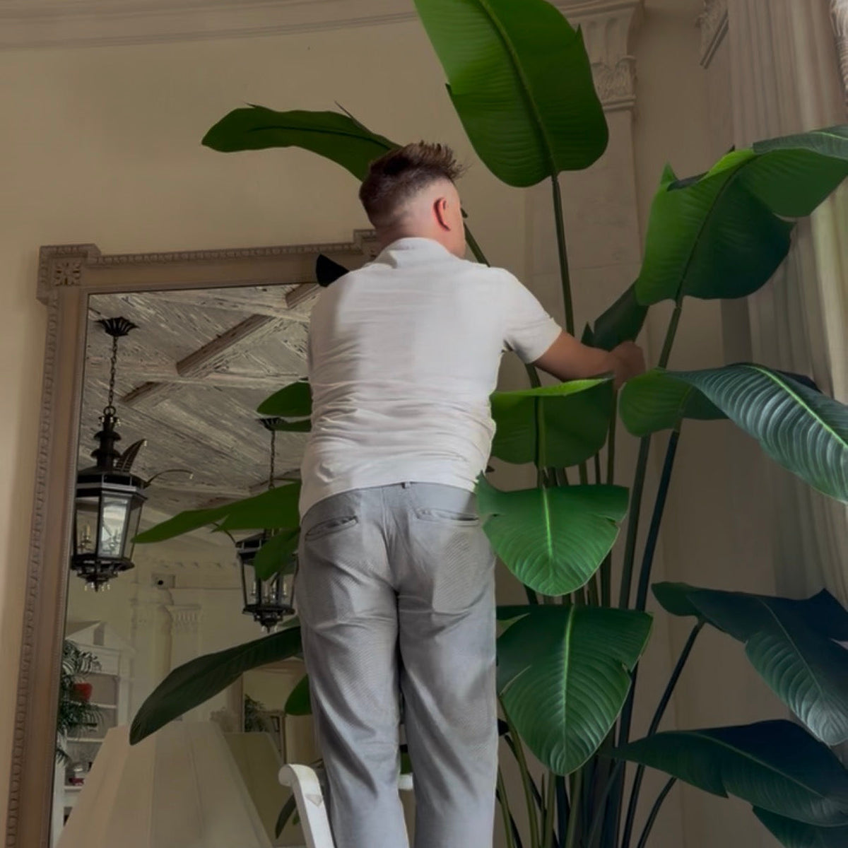 Creative Director of Palm Bungalow Ryan Lewis hand shaping leaves of a faux travellers palm at an estate in Palm Beach Florida.
